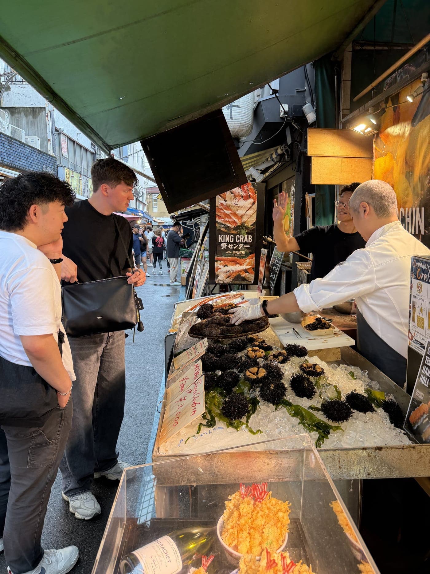 築地場外市場の店先で、店員と言葉を交わしながら食材を選ぶゲスト