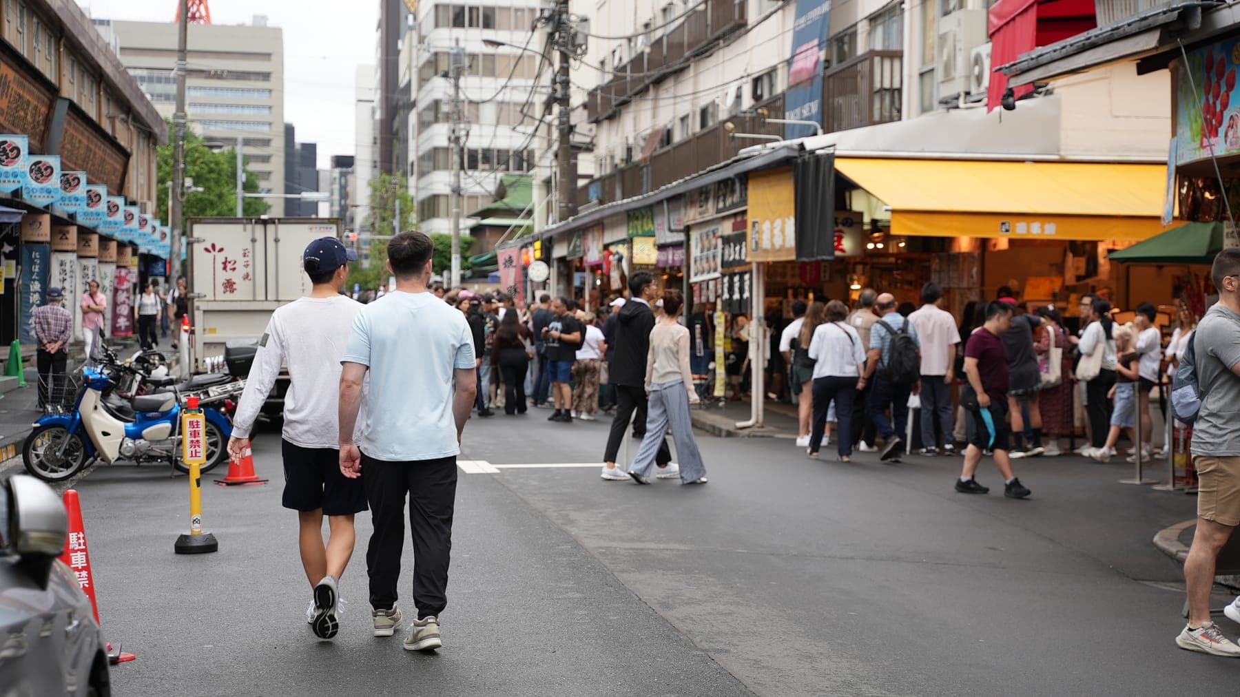 築地場外市場の通りを歩くゲスト。先には店先に集まる人だかりと、軒を連ねる店が続く
